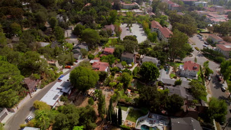 flyover houses and street in eagle rock neighborhood of los angeles towards occidental college campus and parking lot with a blue car driving down the street