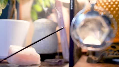 Burning-incense-wand-and-a-swinging-crystal-amulet-background,-spirituality-and-relaxing-concept