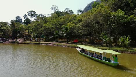 4k daytime drone aerial video with a man steering a boat close to the shores of the laguna de los milagros in tingo maria, peruvian amazon