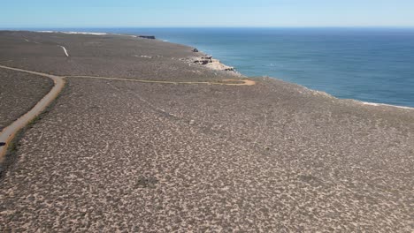 drone aerial of a campervan driving on a long road by a beautiful ocean