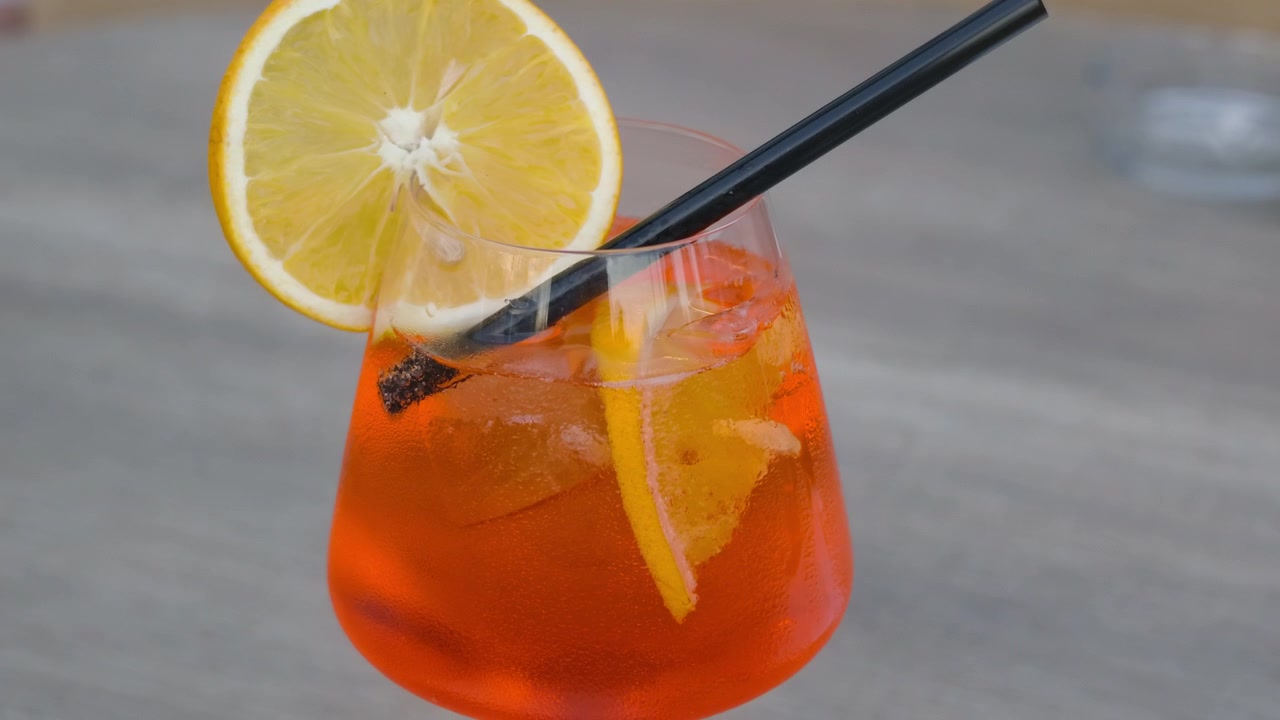 Primo piano di un cocktail spritz all'arancia con ghiaccio, una fetta d'arancia e condensa sul bicchiere