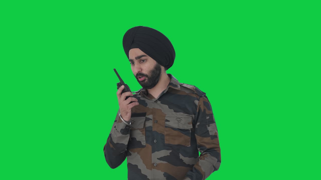 Uomo sikh arrabbiato dell'esercito indiano che urla al walkie-talkie, su schermo verde.
