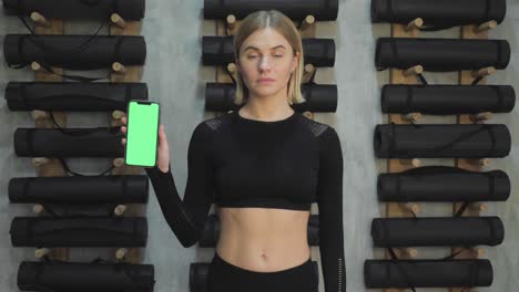 young happy beautiful woman showing smartphone with a green scree