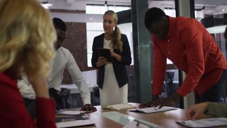 Diverse-group-of-business-colleagues-brainstorming-in-meeting-room-using-tablet