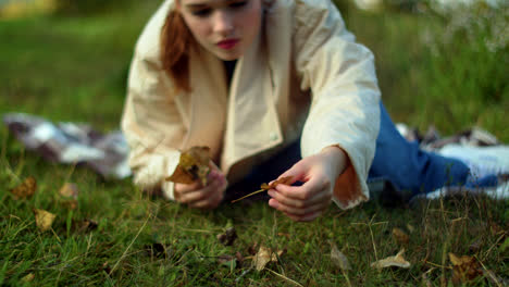girl picking leaves in autumn park