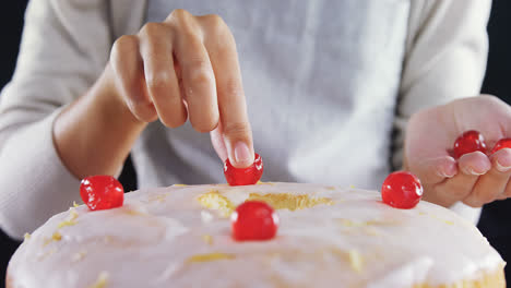 Woman-topping-a-fresh-baked-cake-with-cherry-4k