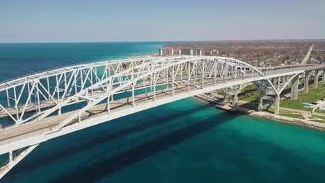 Blue-Water-Bridge-connecting-Port-Huron,-Michigan-USA-and-Sarnia,-Ontario-Canada-with-drone-moving-down