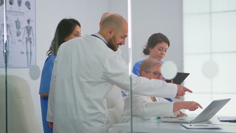 médico sénior usando una computadora portátil explicando a sus colegas el tratamiento de los pacientes