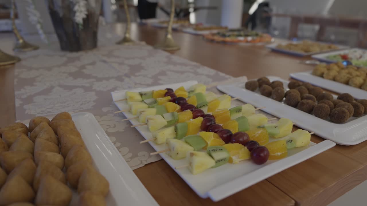 Pezzi di frutta assortiti e snack disposti su vassoi da portata a buffet.