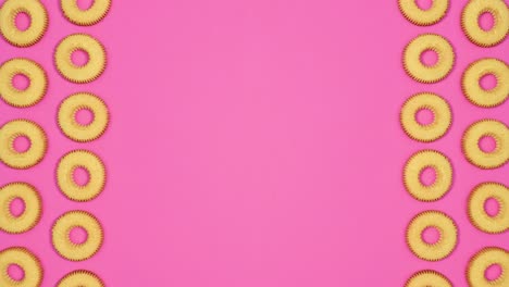 biscuit cookies move on left and right side of vibrant pink background with copy space. stop motion flat lay