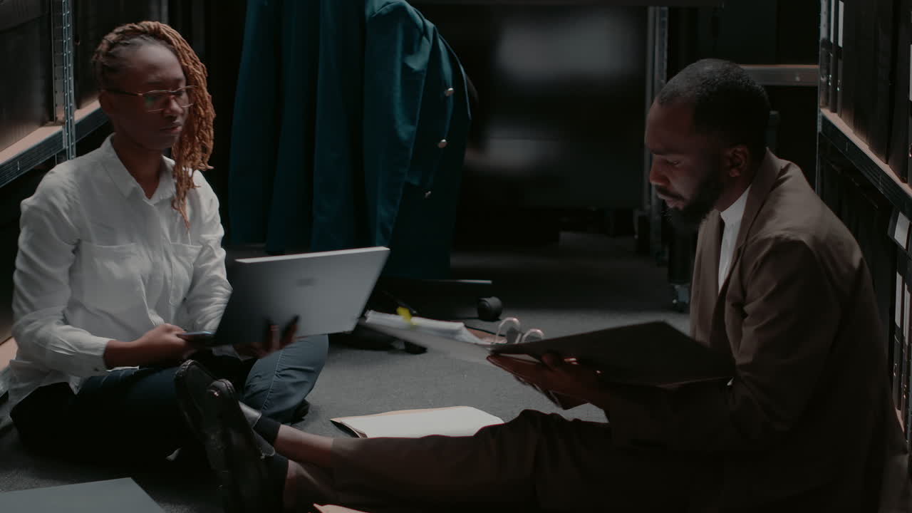 Two people sitting on the floor with papers and laptop