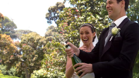 groom popping bottle of champagne with new wife
