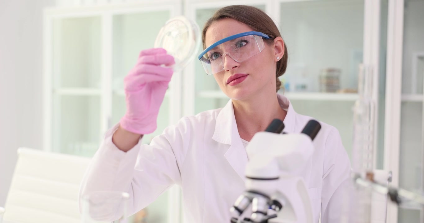 Medical professional observes sample within petri dish