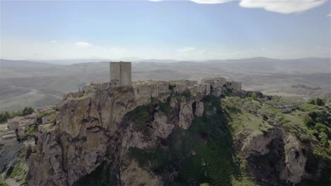 drone flying backwards away from the old ruins of craco on a hilltop in the south of italy in 4k