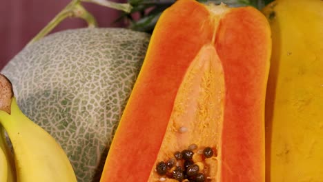 a colorful arrangement featuring pomegranate, bananas, papaya, rockmelon, pineapple, kiwi, and orange slices.