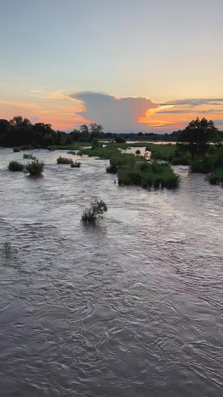 Il sole tramonta dietro una drammatica formazione nuvolosa sul fiume Sabie nel Parco Nazionale Kruger, Sudafrica. Ideale per documentari naturalistici o contenuti di viaggio.