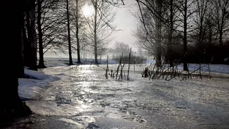 Foggy-stream-in-peaceful-landscape,-elderly-couple-crossing-bridge-in-background