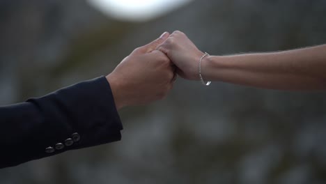 mano masculina y femenina que se alcanzan sosteniendo suavemente y saliendo lentamente de nuevo - traje y pulsera
