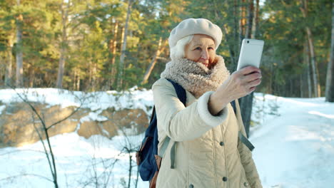 senior woman taking a selfie in a snowy forest