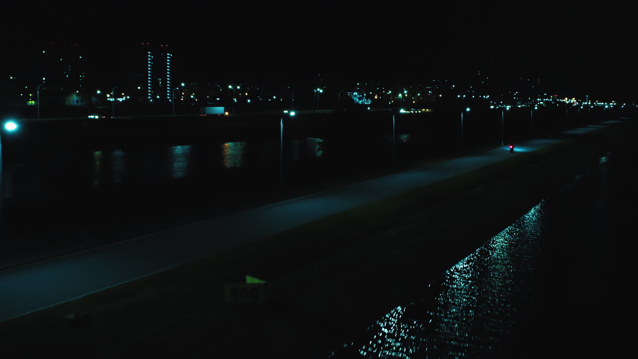 vuelo desde una altura detrás de una motocicleta deportiva corriendo a lo largo del río contra el telón de fondo de la