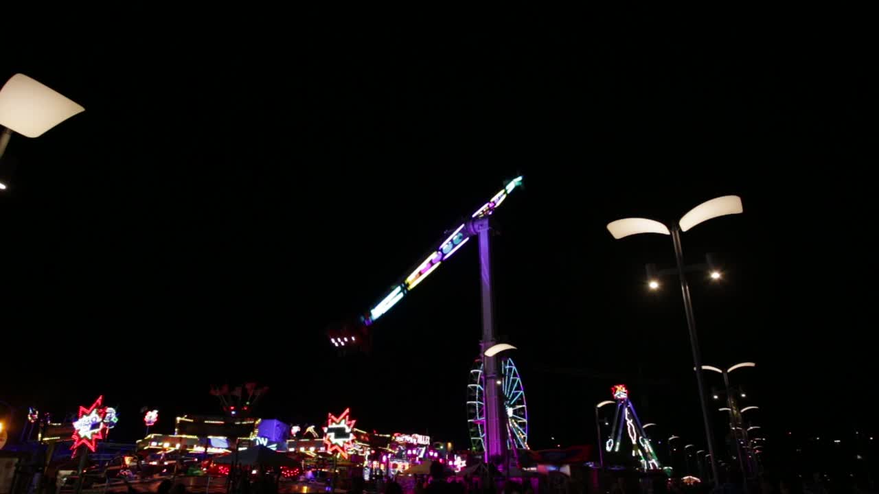 A Booster Pendulum Ride Illumined In Lights Slowly Rotating Against Night Sky In Kasprowicz Park In Szczecin, Poland - Low-Angle Shot