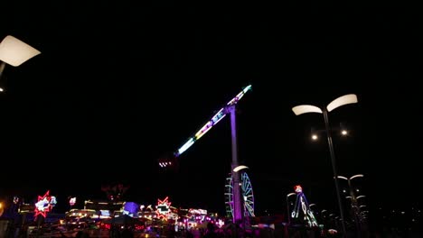 a booster pendulum ride illumined in lights slowly rotating against night sky in kasprowicz park in szczecin, poland - low-angle shot