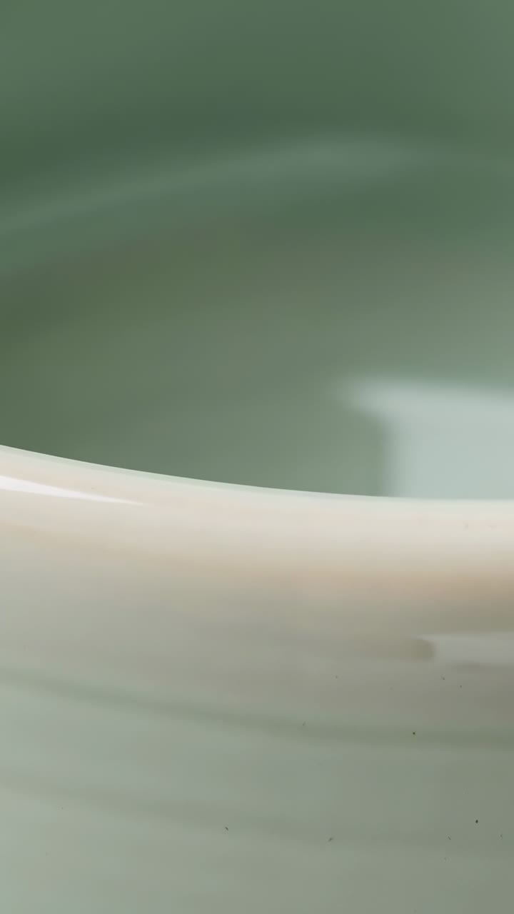 Video verticale: cambio di angolazione della camera che rivela il bordo smaltato di un recipiente in studio, mostrando una leggera evidenziazione a forma di scatola