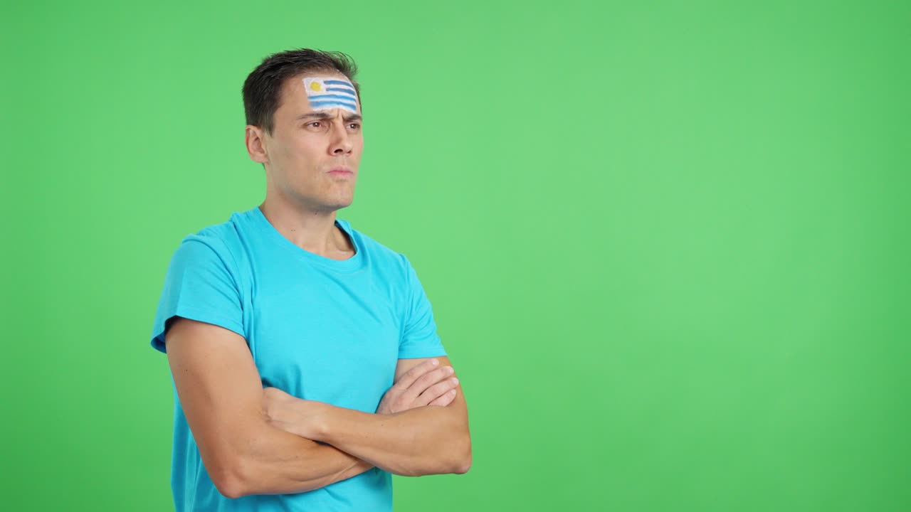 Man with uruguayan flag painted looking away with serious expression