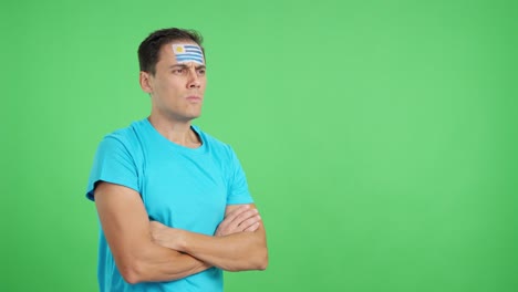 man with uruguayan flag painted looking away with serious expression
