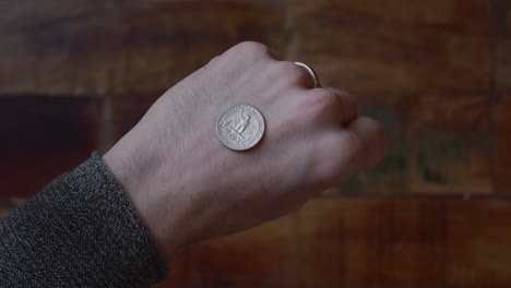 man place the quarter dollar coin at the back of his hand