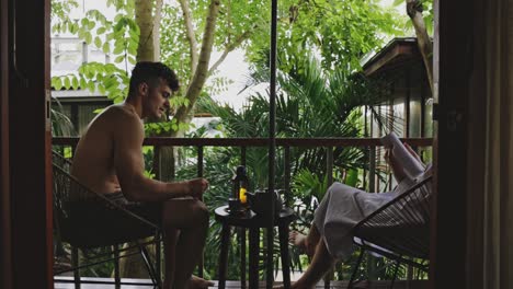 couple in balcony drinking tea and reading with a view of luscious green plants