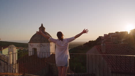 mujer joven feliz brazos de turista levantados celebrando un viaje exitoso vacaciones disfrutando de la libertad independiente relajándose en el balcón al atardecer