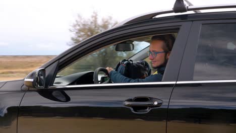 slow motion shot of a young man driving the car and parking ready to go for a hike