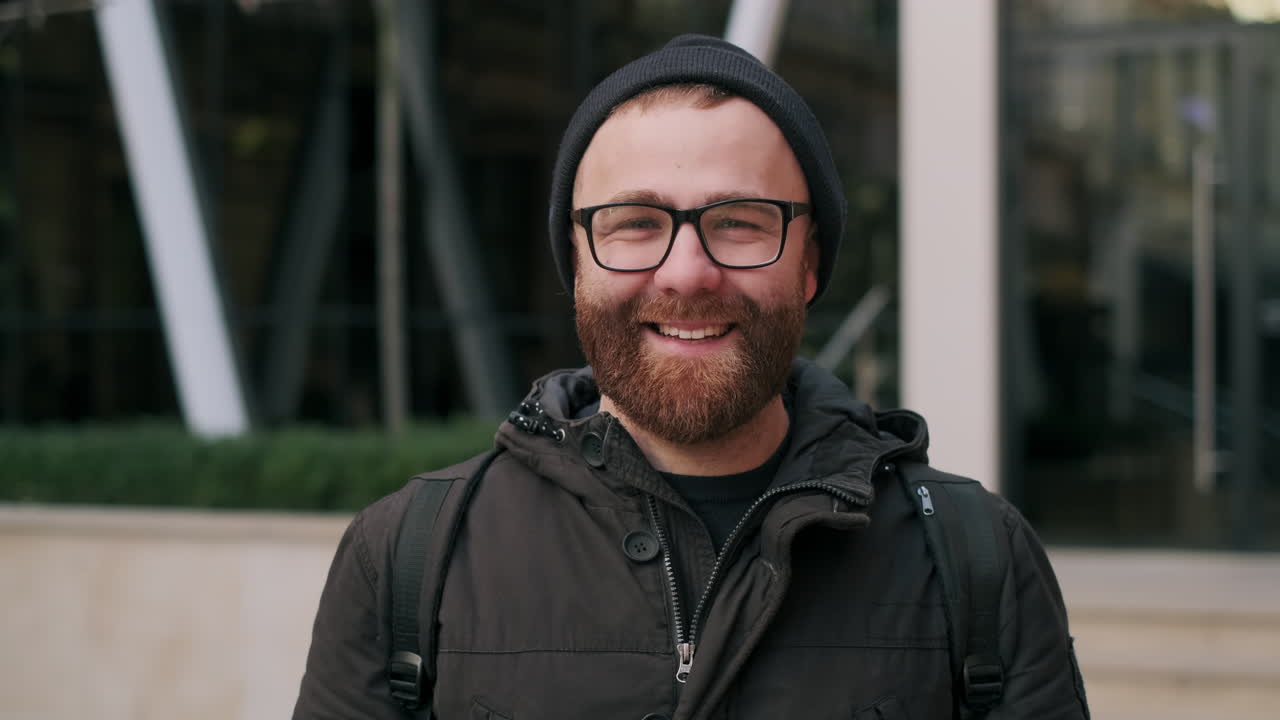 Uomo felice con barba, occhiali e berretto che sorride