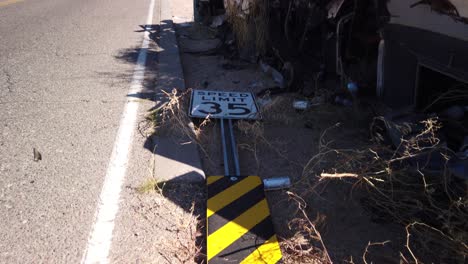 inclínate desde una señal de límite de velocidad derribada junto con un remolque quemado arrojado ilegalmente y basura en la carretera, scottsdale, arizona