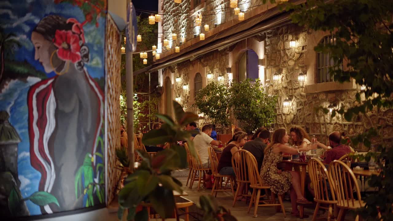 Greek taverna (outdoor cafe) vibrant and colourful atmosphere at night, Beautiful street wall art, Handheld gimbal shot
