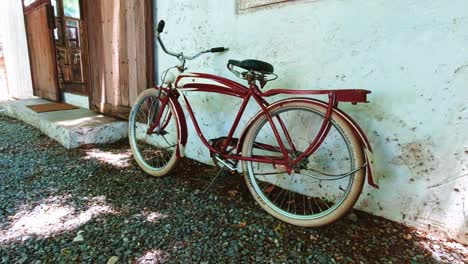 classic red bicycle resting against a white wall next to a sliding door entrance to a cafe in bangkok, thailand