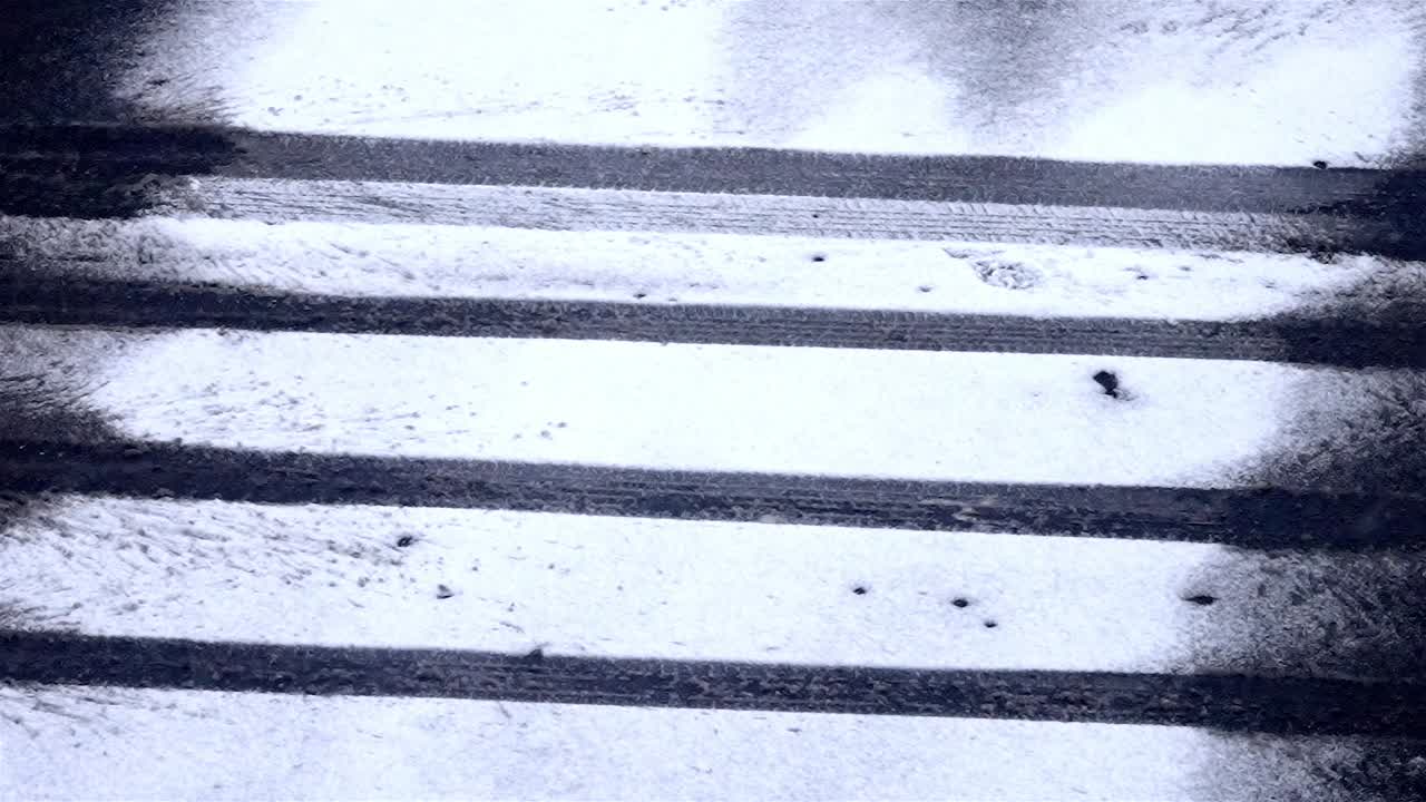 Slow falling snowflakes on a street, pattern of the car wheels in the snow covered road, static shot, copy space