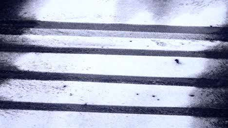 Slow falling snowflakes on a street, pattern of the car wheels in the snow covered road, static shot, copy space