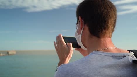 male tourist is photographing seascape in daytime using smartphone camera at the port of puerto ingeniero white, buenos aires, argentina