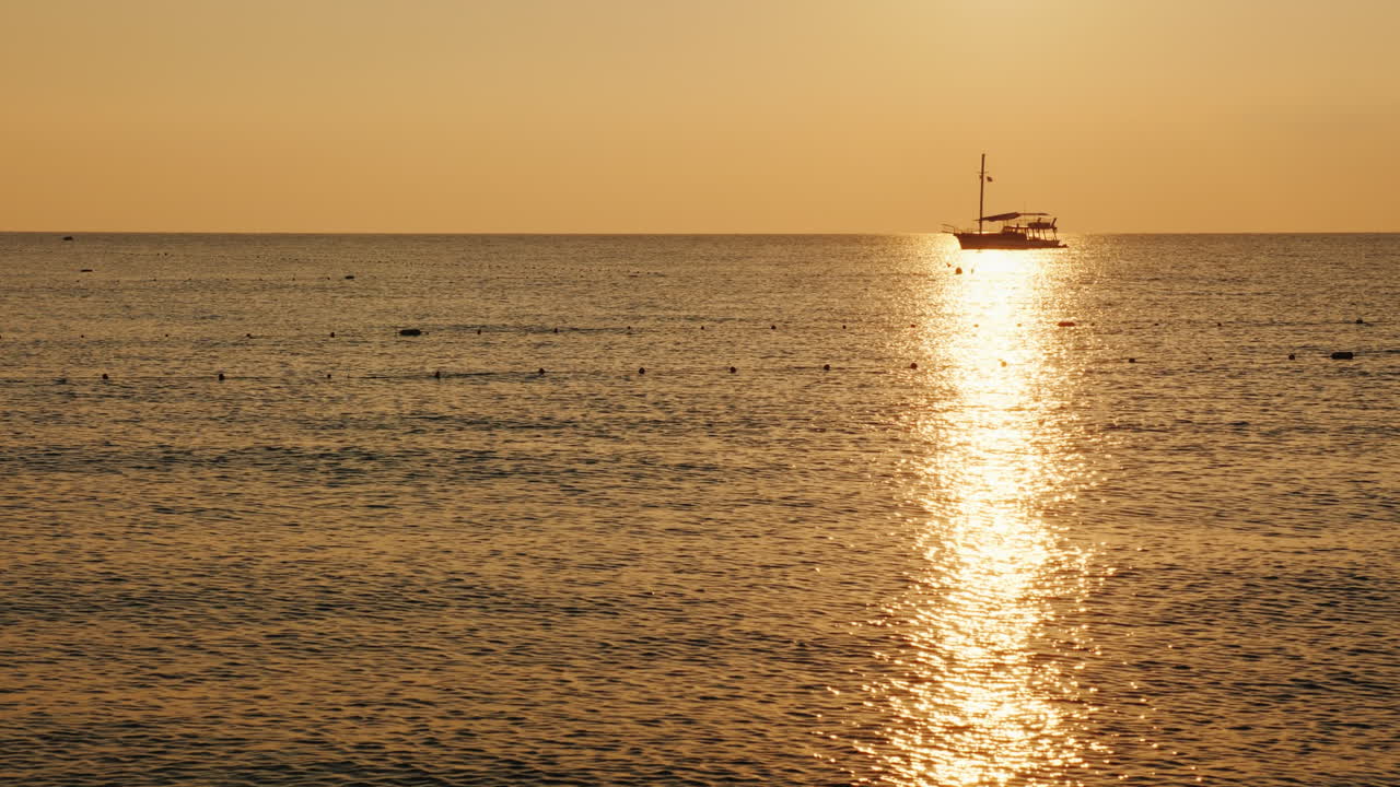 해가 뜰 때 바다에 있는 낚싯배는 물 4k 비디오 위의 빛나는 길에서 아름다운 실루엣을 보여줍니다
