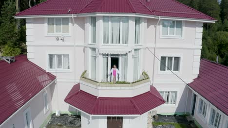 vista aérea de una casa rosa con una mujer en el balcón