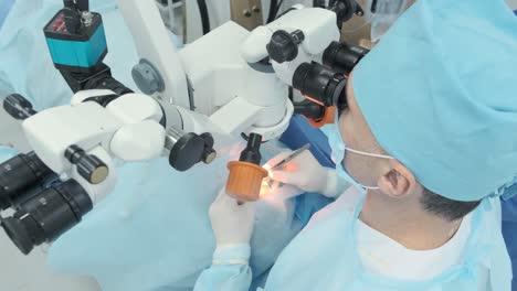 surgeon looking into the microscope at the eye of female patient at the operating room. doctor using microscope during eye surgery process, treatment of cataract and diopter correction.