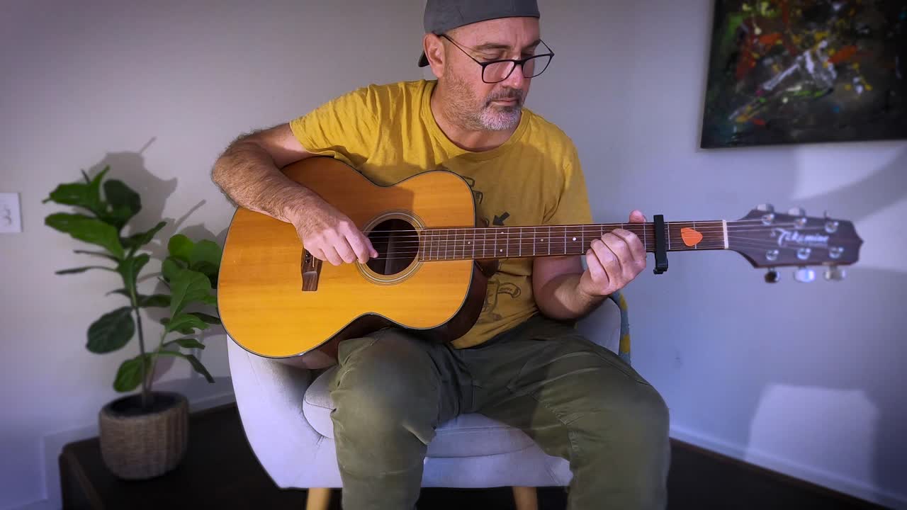 un hombre de mediana edad tocando la guitarra acústica en un pequeño escenario