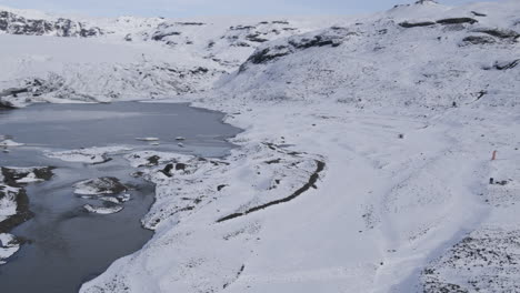 Establishing-aerial-shot-of-a-group-of-parachuters-landed-within-a-snowy-Iceland-valley