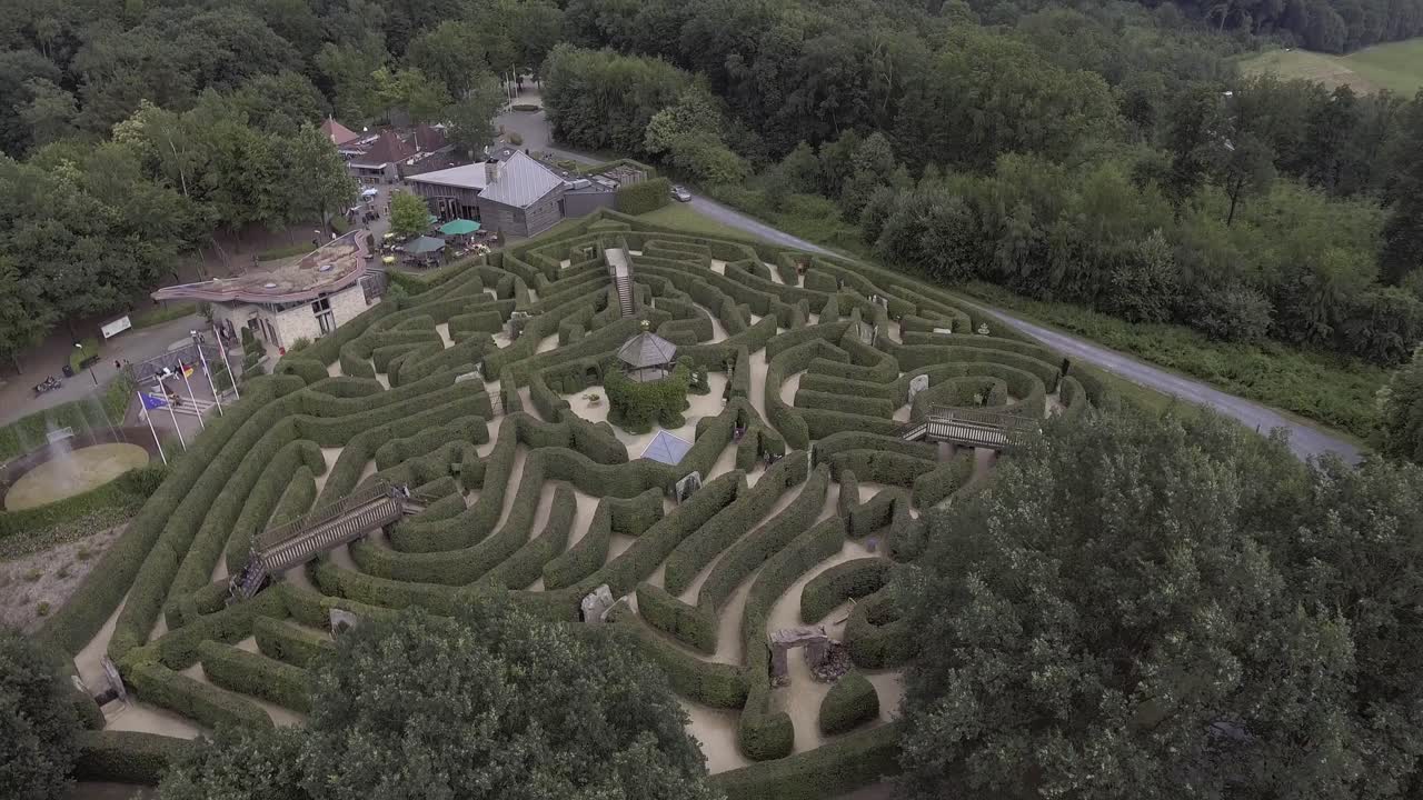A drone shot, flying up and panning down, revealing a maze behind the trees in the Netherlands