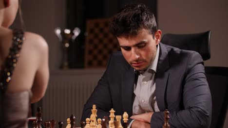 Young-caucasian-man-thinks-about-next-move-playing-chess-game-against-woman