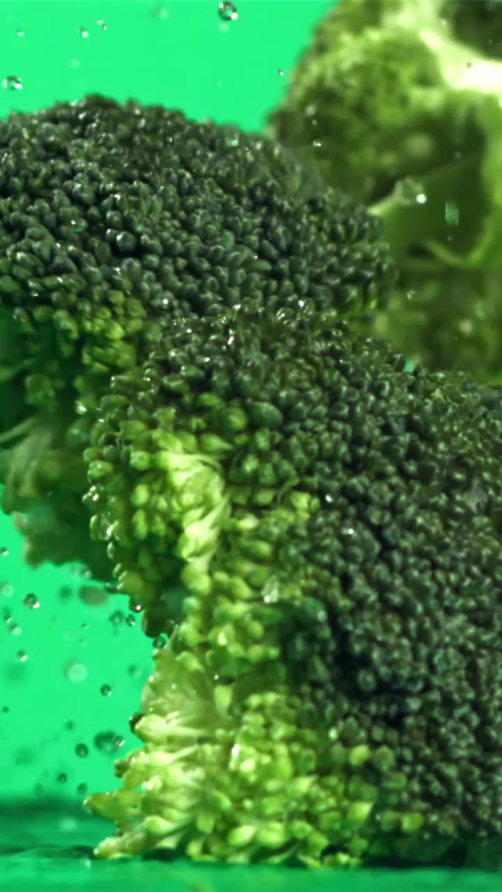 Cimette di broccoli verdi freschi che cadono nell'acqua