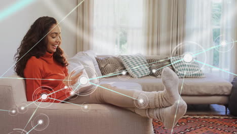 animación de una red de círculos conectados sobre una mujer biracial feliz usando un teléfono inteligente