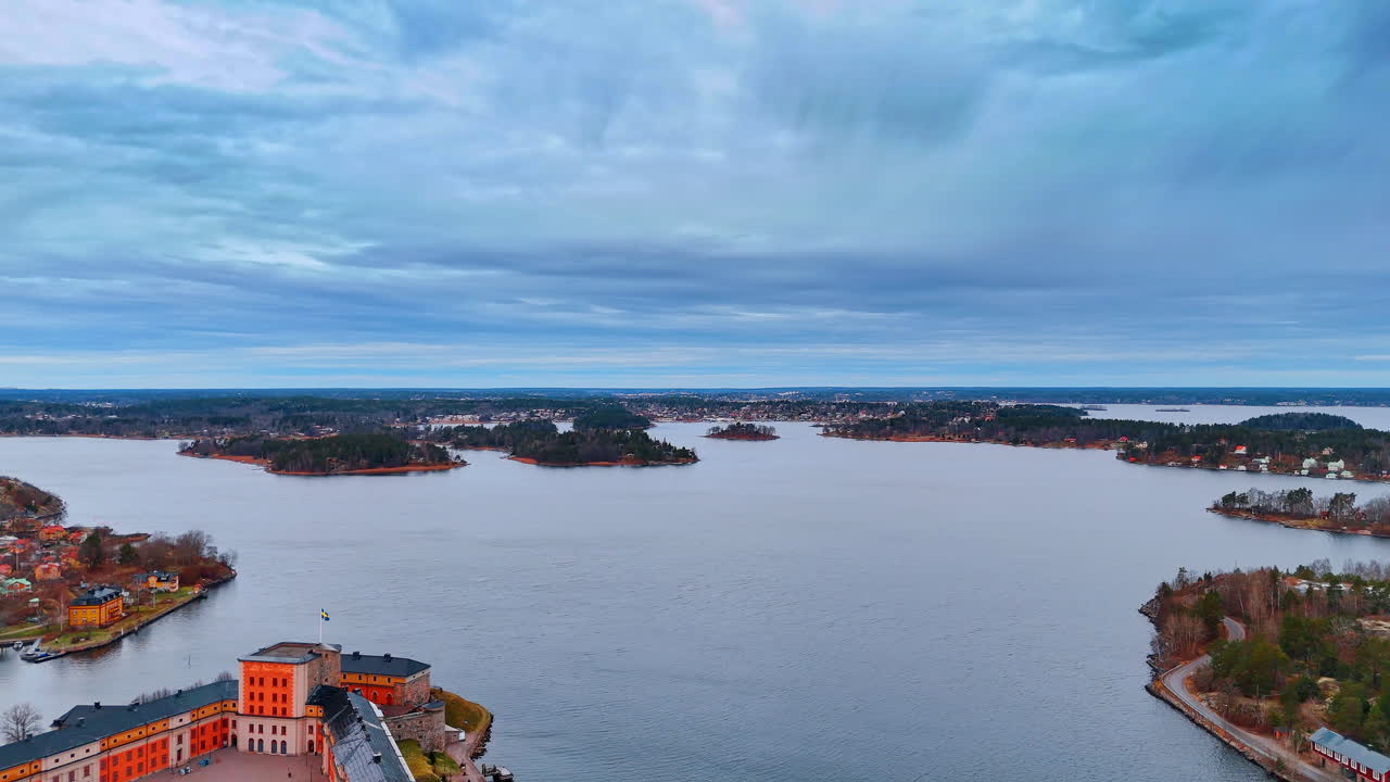 Pemandangan sudut tinggi halaman benteng Vaxholm dan kepulauan. Perspektif udara bangunan benteng bersejarah berwarna oranye dengan halaman yang terletak di sebuah pulau di Swedia